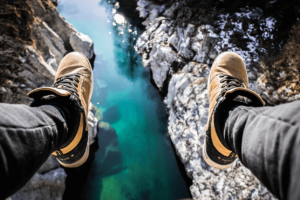 Legs hanging over a cliff overlooking a river